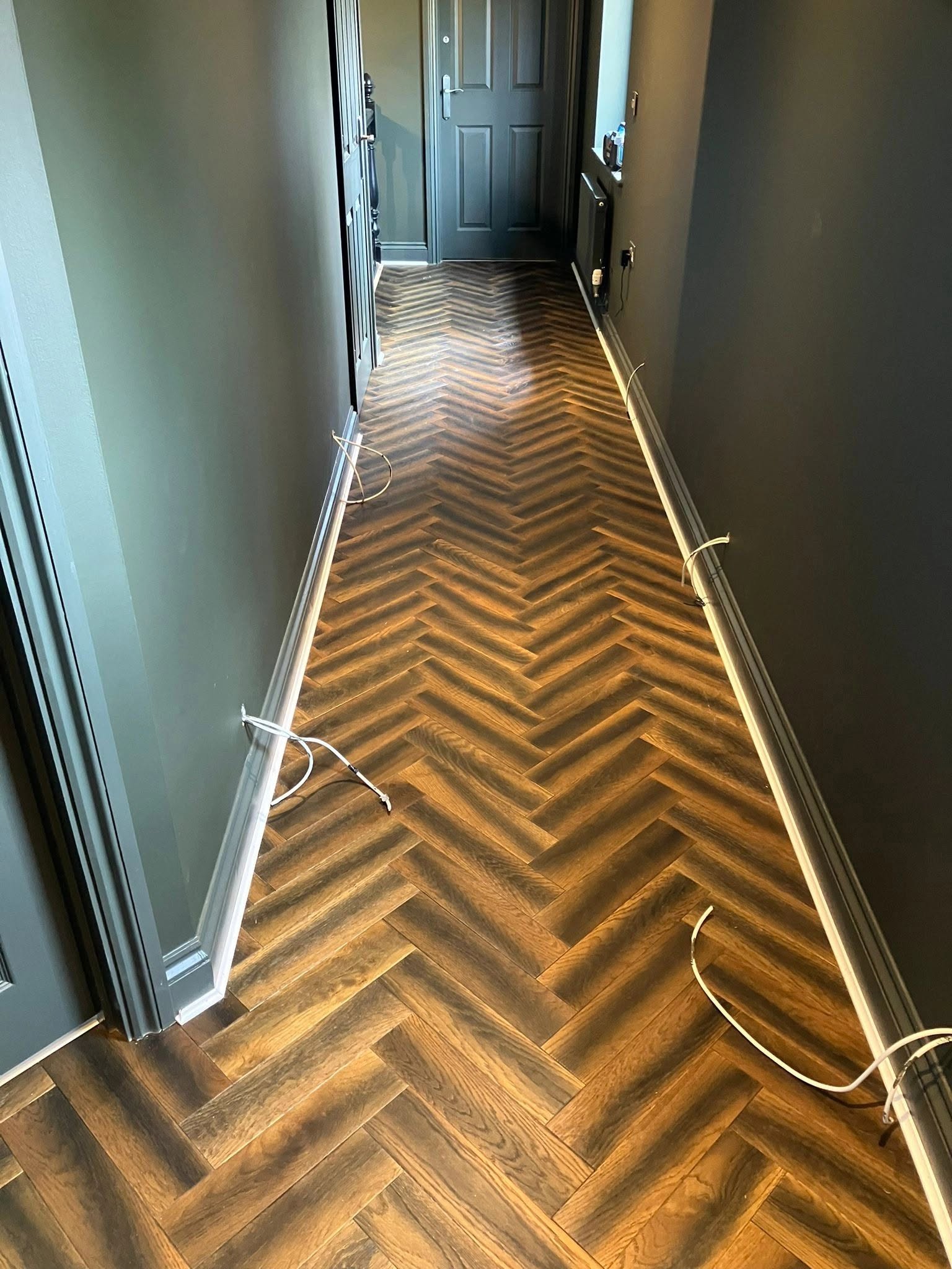 Richly coloured herringbone floor in a narrow hallway