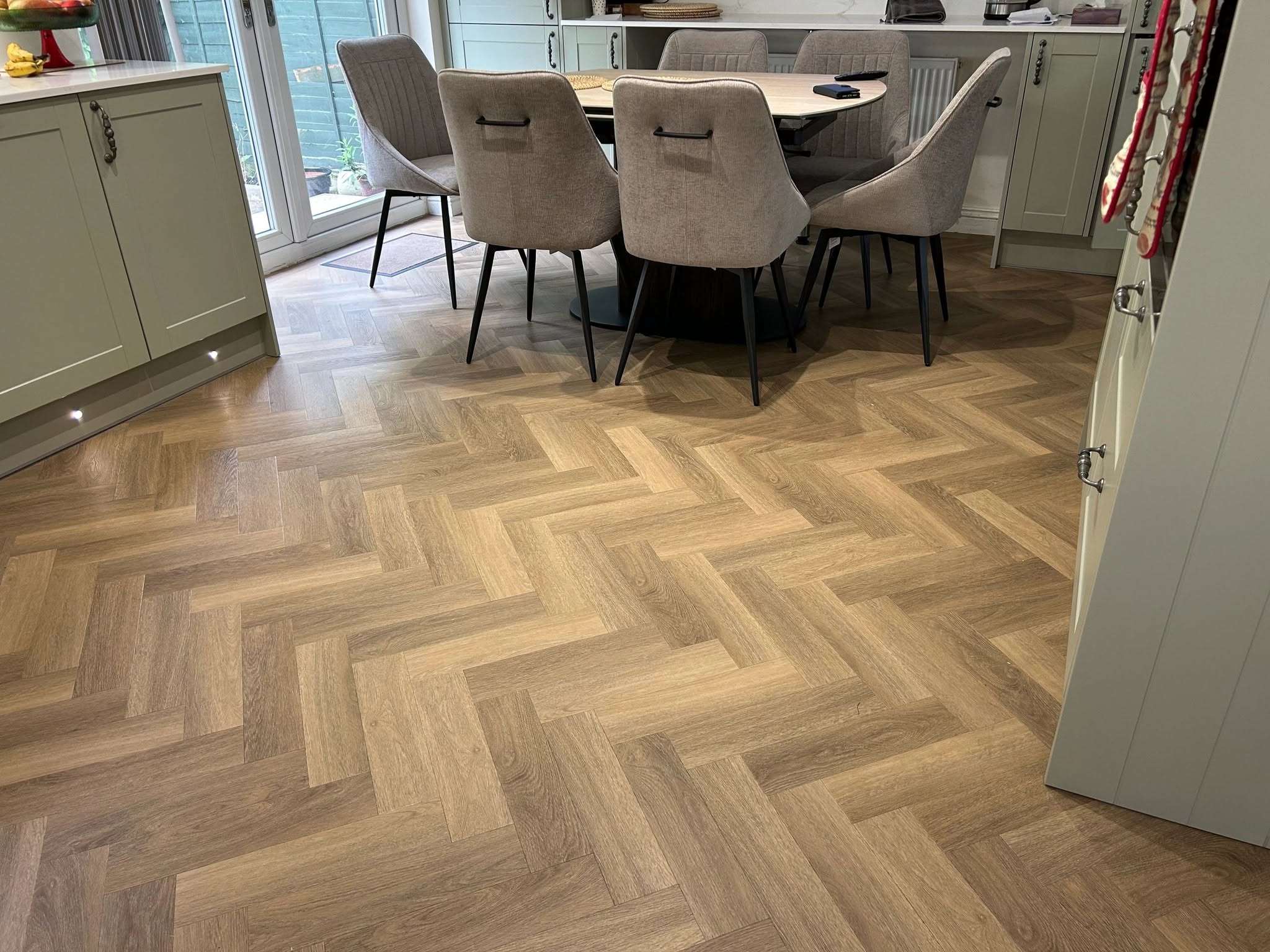 Oak herringbone flooring flowing through a kitchen and dining room